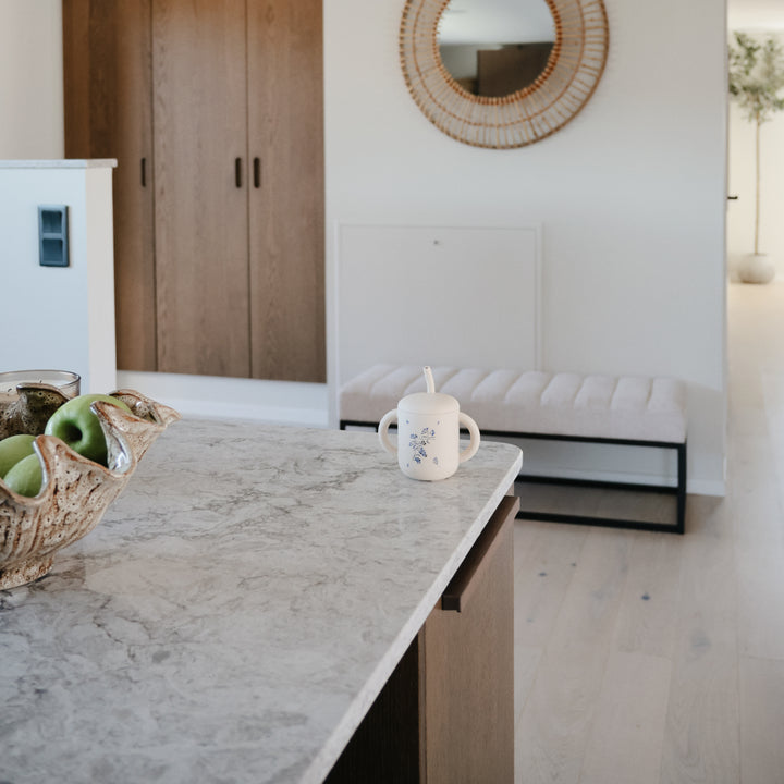 Modern kitchen with marble countertop, wooden cabinets, and a white bench.