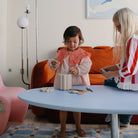 Two children playing with a toy on a table in a living room.
