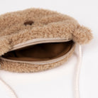 A close-up of a beige sherpa fleece crossbody bag with a zippered compartment and cream-colored drawstring, shown on a white background.