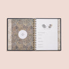 Open planner with floral design on cover and white pages on a beige background