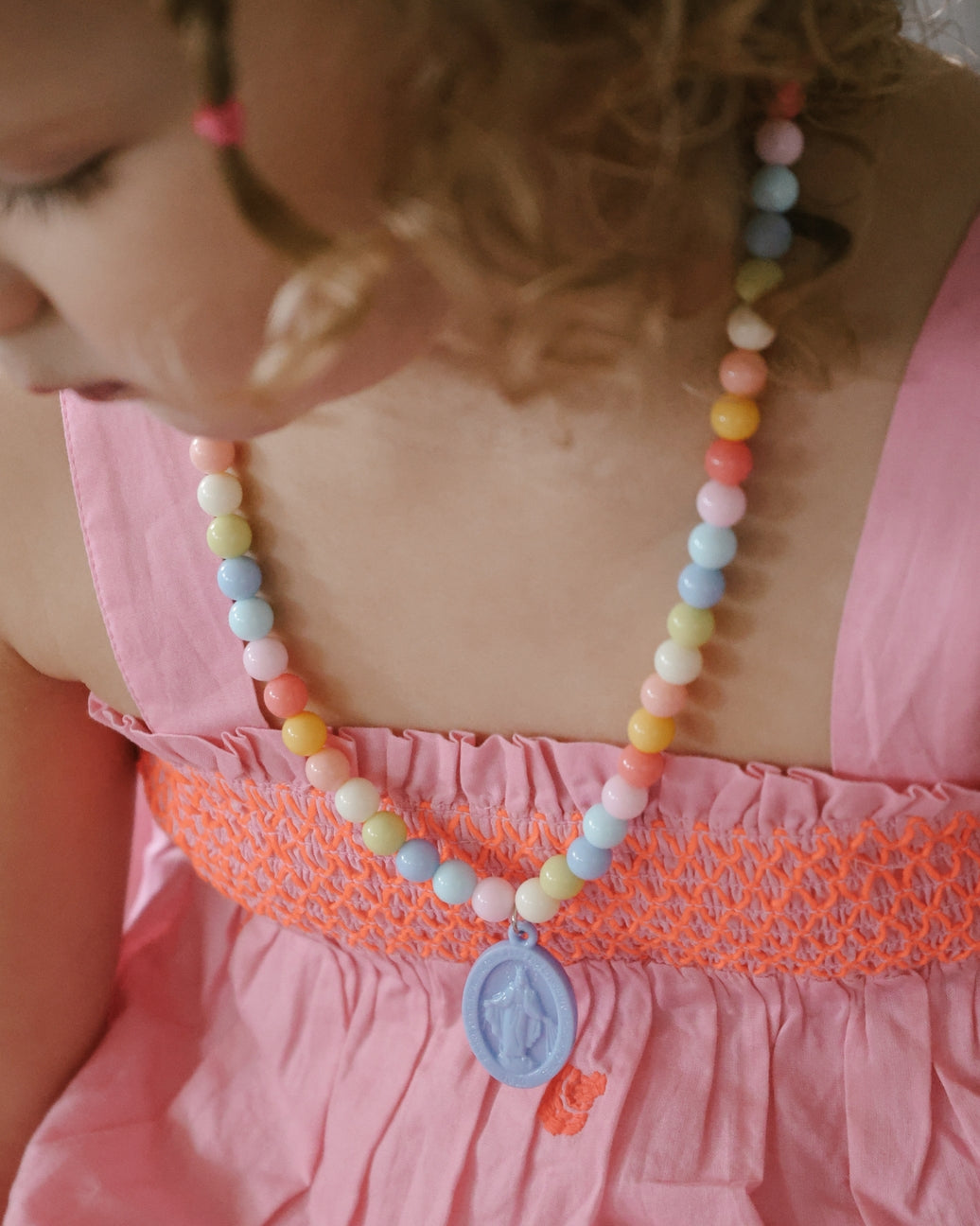 Child wearing a colorful beaded necklace with a pink dress