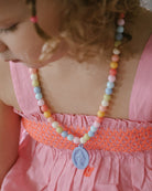Child wearing a colorful beaded necklace with a pink dress