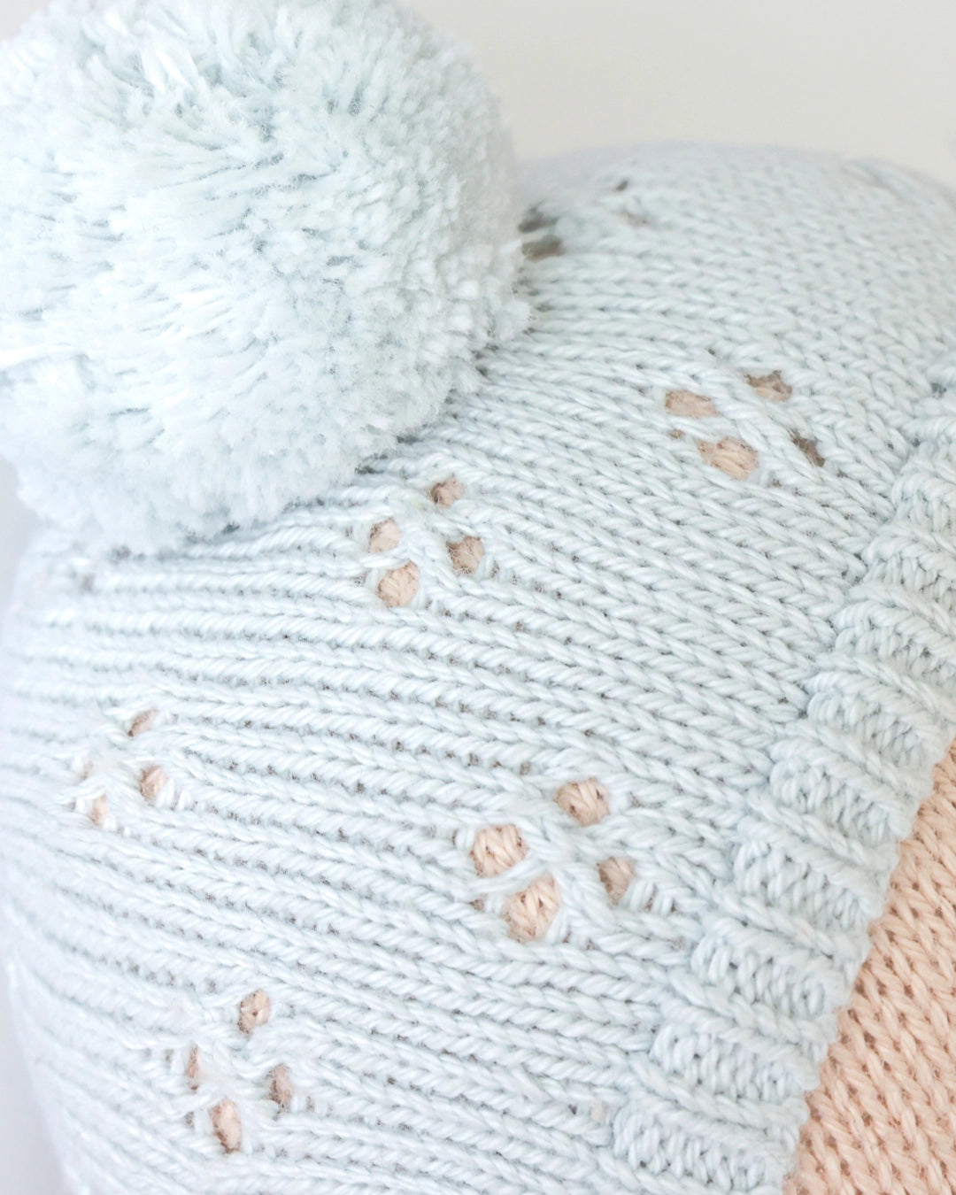 Close-up of a light blue knitted blanket with paw print patterns on a white background