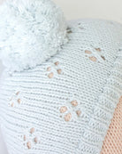 Close-up of a light blue knitted blanket with paw print patterns on a white background
