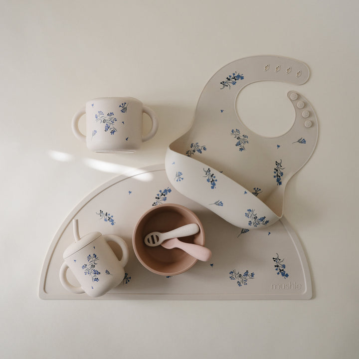 Children's tableware set with cups, bowl, and bib on a white background