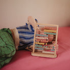 Wooden abacus with colorful beads on a pink surface
