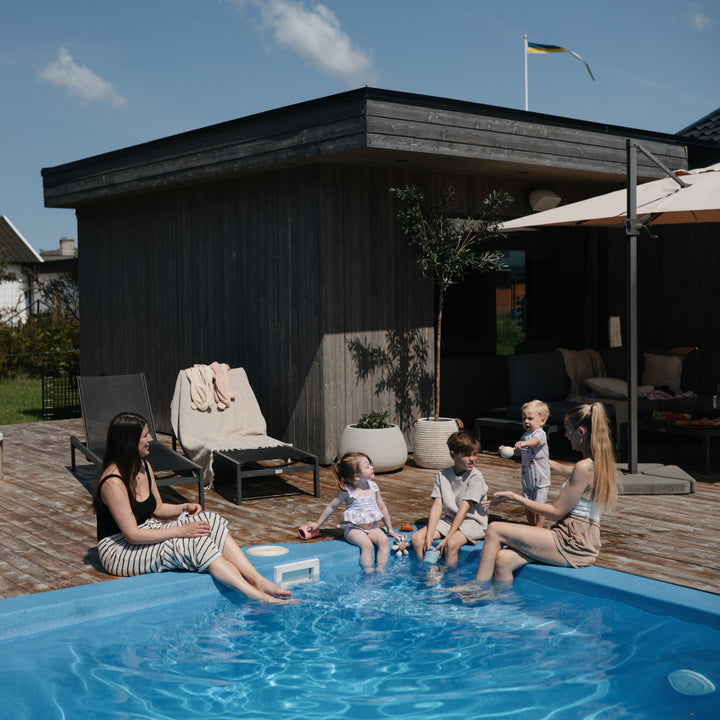 People by a pool with a modern house and garden in the background