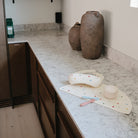 Decorative items on a marble countertop with large vases in the background.