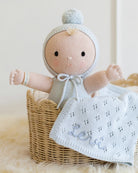 Knitted baby doll with a blanket in a basket on a soft surface