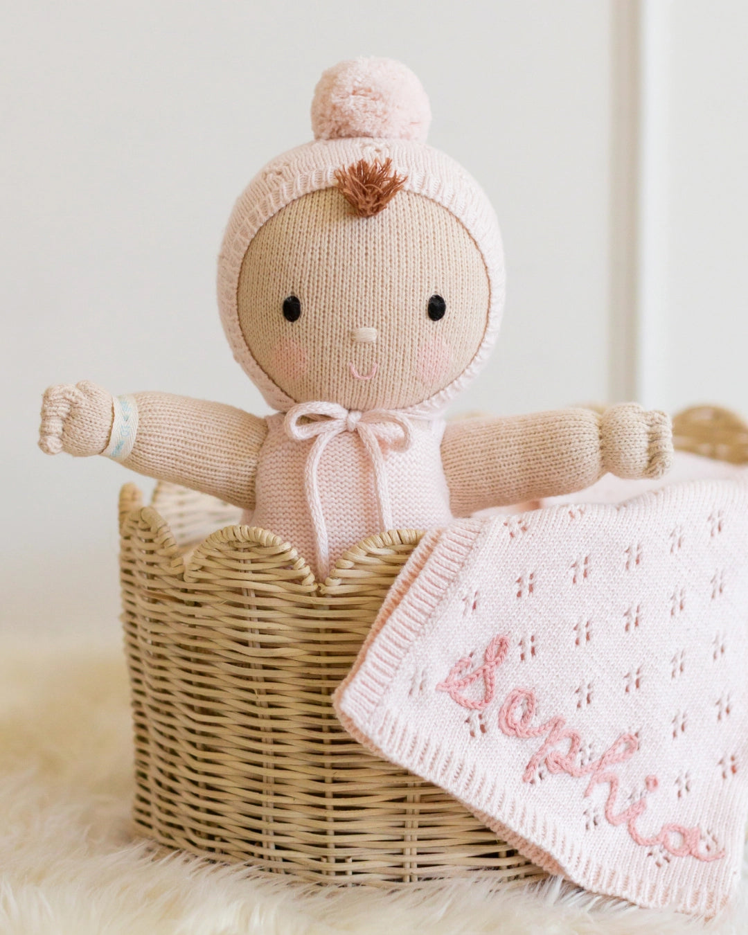 Knitted doll with biege outfit and blanket named 'Sophia' in a basket