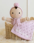 Knitted doll with pink outfit and blanket named 'Olivia' in a basket