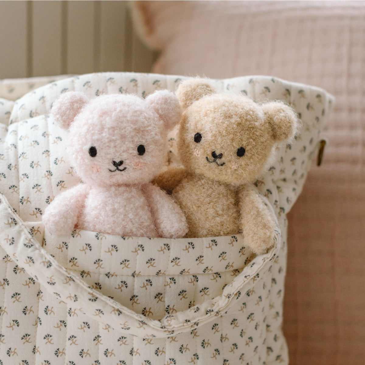 Two teddy bears in a patterned fabric basket.