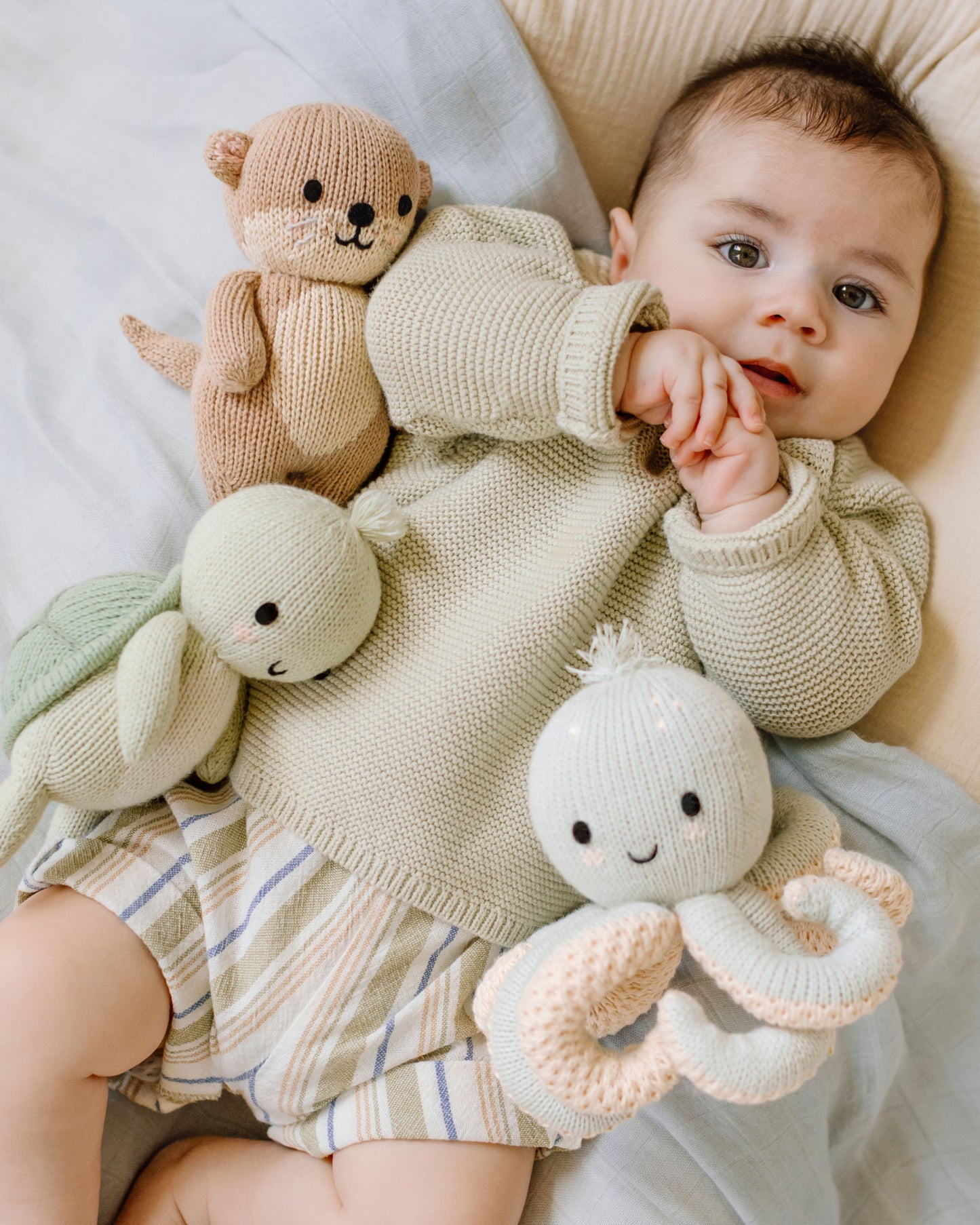 Baby with a knitted teddy bear and octopus on a soft surface