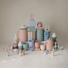 Collection of colorful ceramic items including cups and vases on a neutral background
