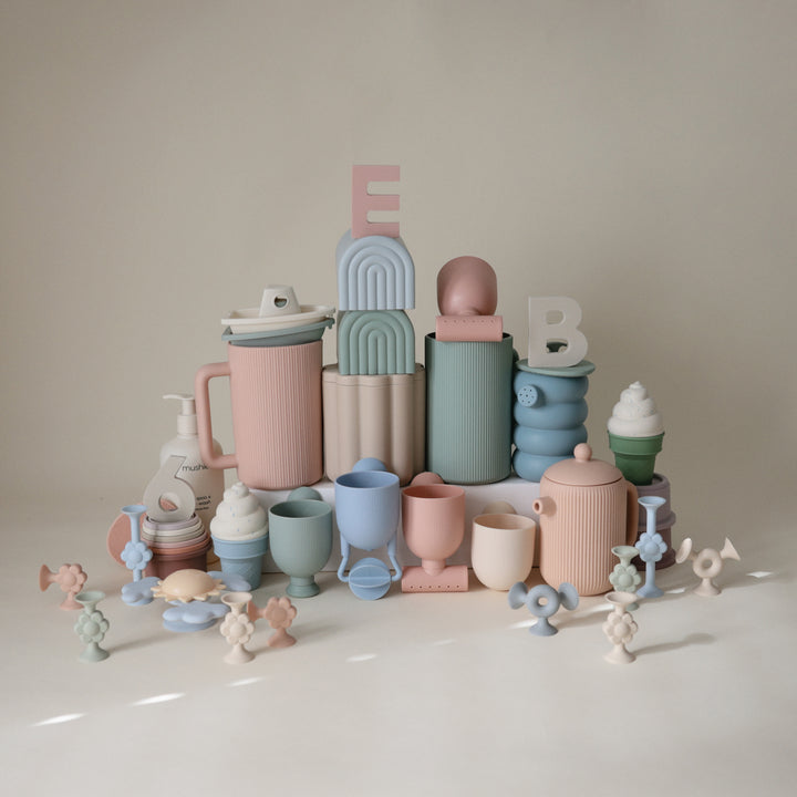Collection of colorful ceramic items including cups and vases on a neutral background