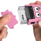 Pink Markr by OOLY stamp with cartoon face held by a hand on a white background