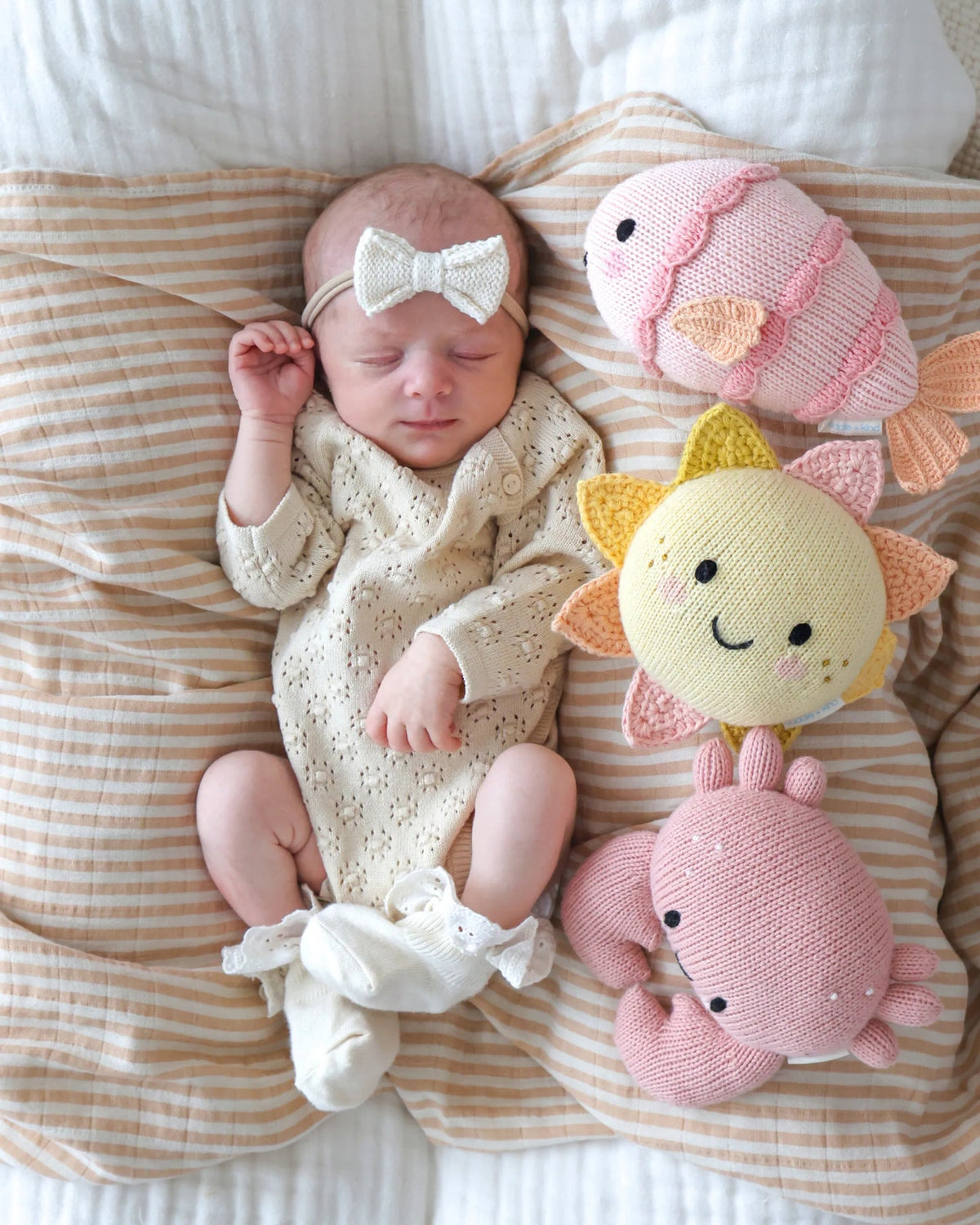  A sleeping newborn with a knitted toys shaped like a sun, a crab, and a fish