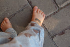 Child's feet with a small tattoo on a stone pavement
