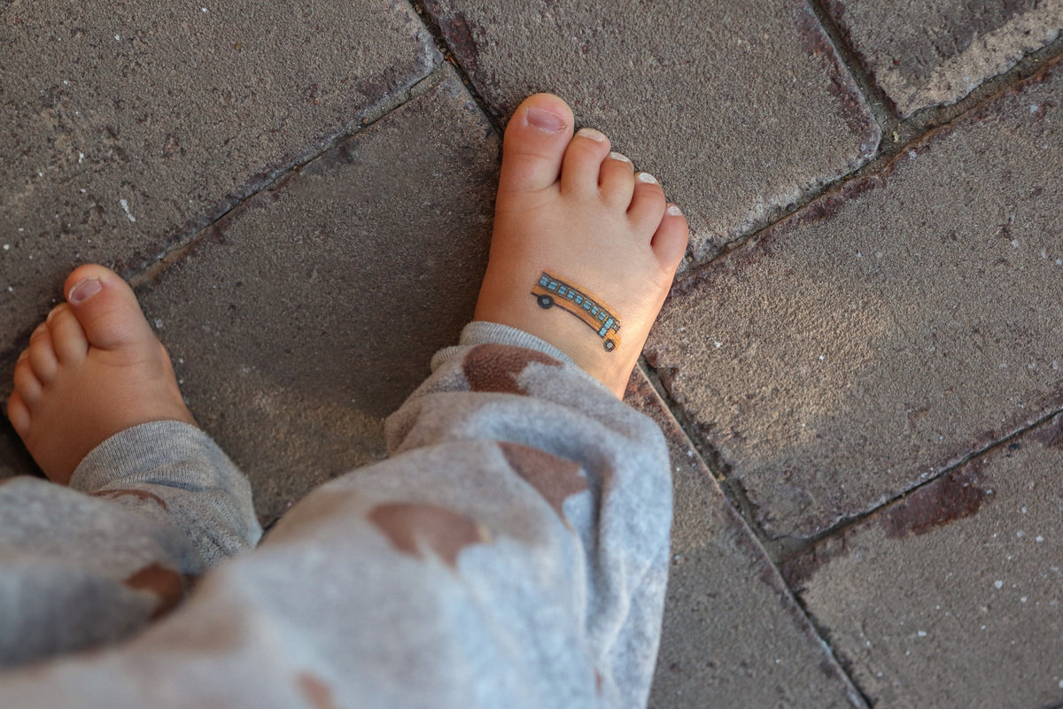 Child's feet with a small tattoo on a stone pavement