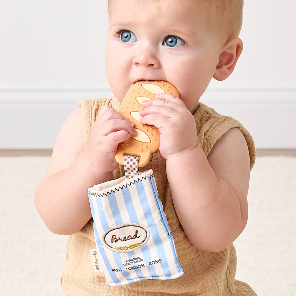 Baby holding a toy shaped like a bag of bread
