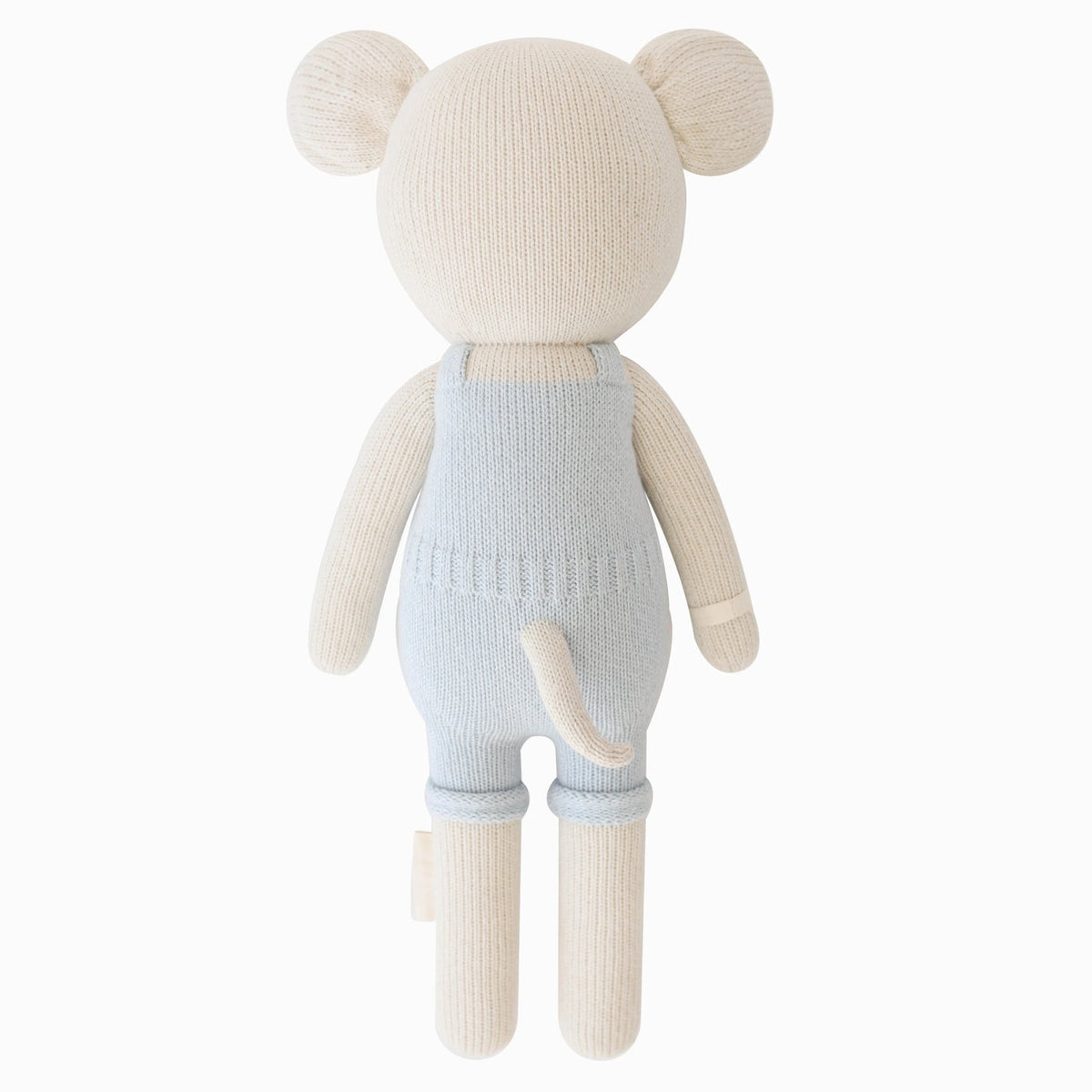 Knitted teddy bear wearing light blue overalls on a white background