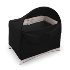 A black room-darkening canopy fitted over an UPPAbaby Remi V2 playard against a dark checkered background.