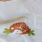 Embroidered design of a deer on a white fabric background