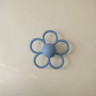 Blue flower-shaped teething ring on a beige background