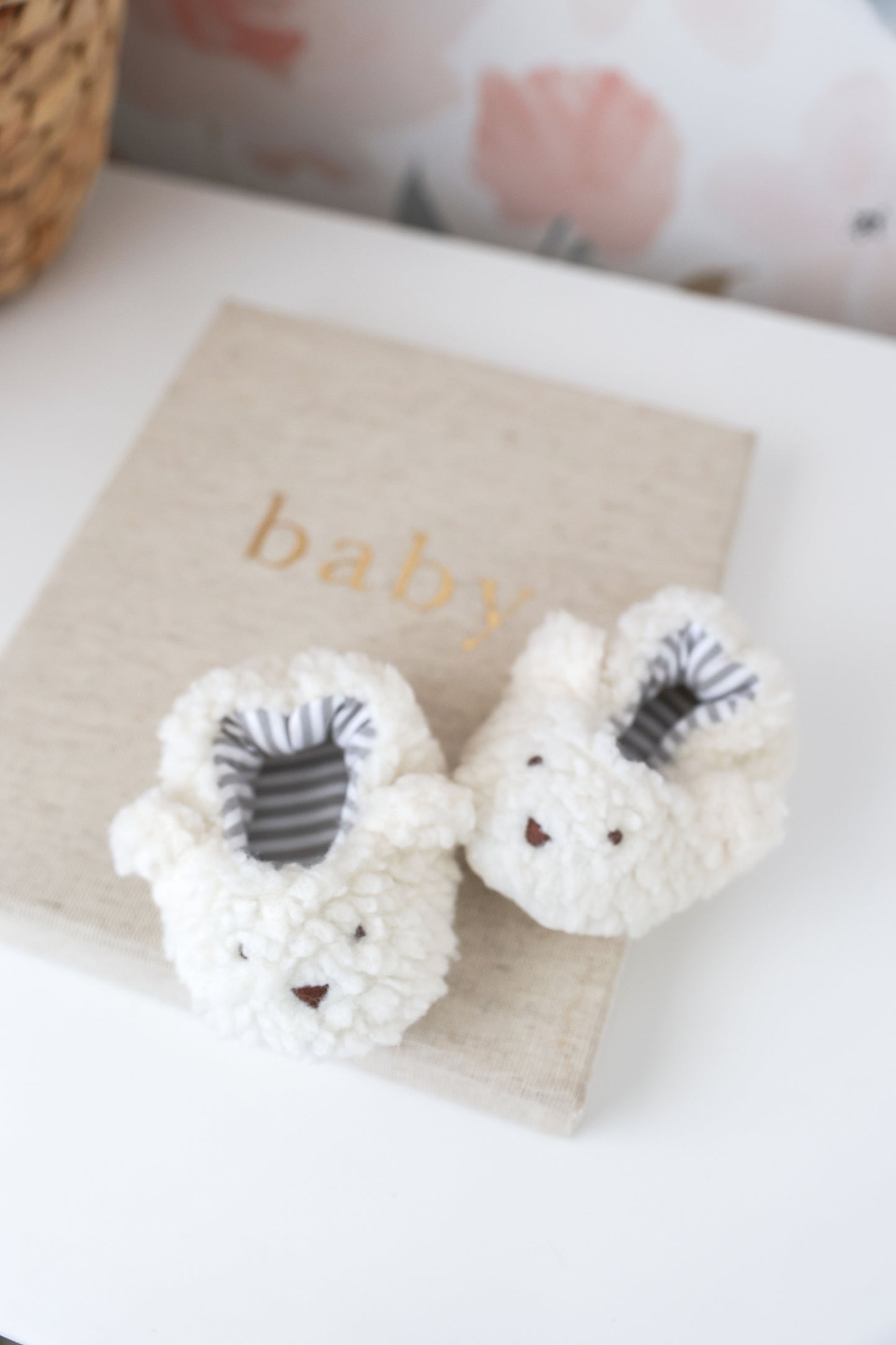 White baby booties with gray accents on a beige blanket labeled 'baby'.