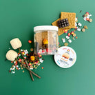 Miniature food items and a jar on a green background with a small round label.