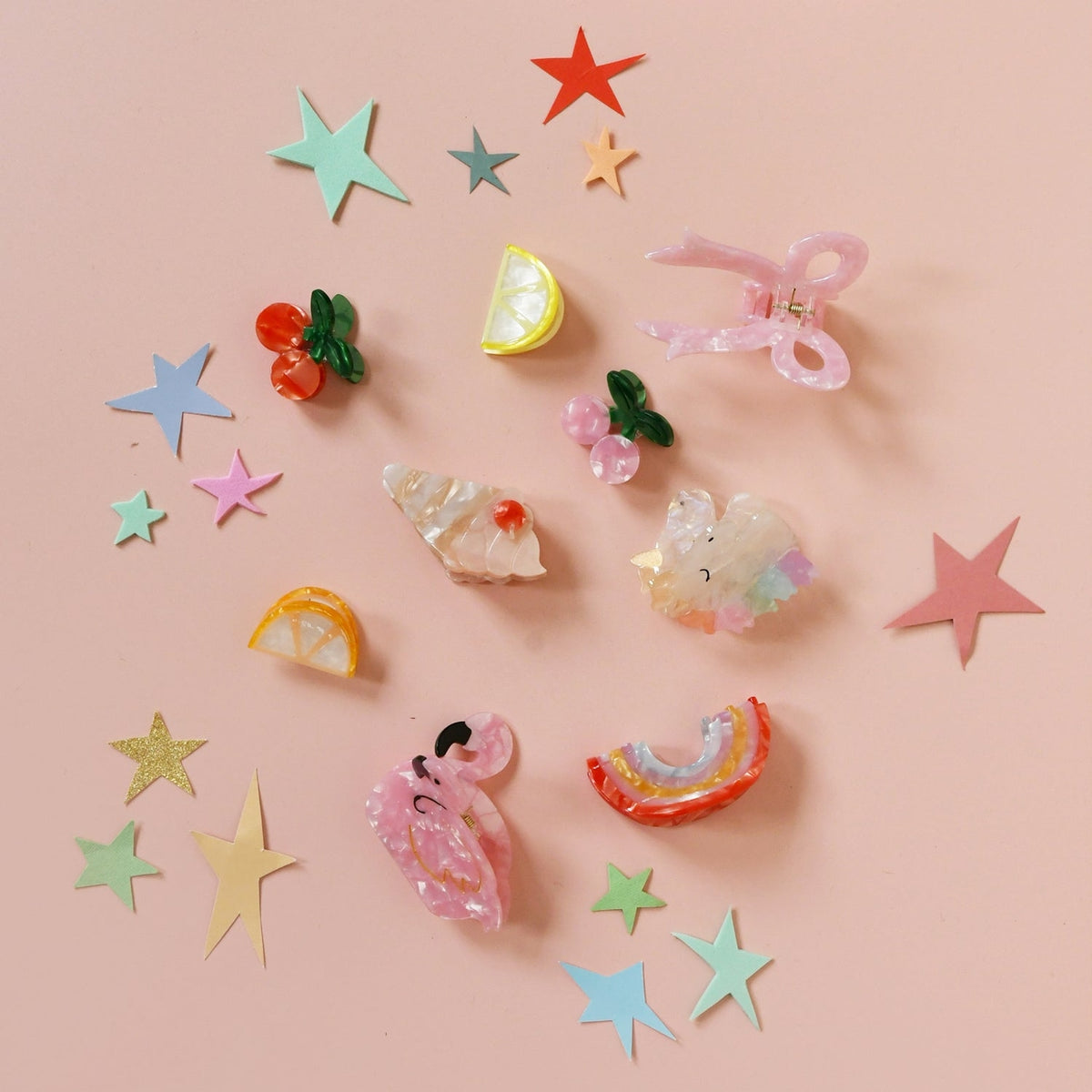 Colorful hair accessories including stars and cartoon designs on a pink background