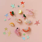 Colorful hair accessories including stars and cartoon designs on a pink background