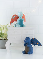 Two dragon figurines with star-patterned wings on a white surface with a light-colored wall background.