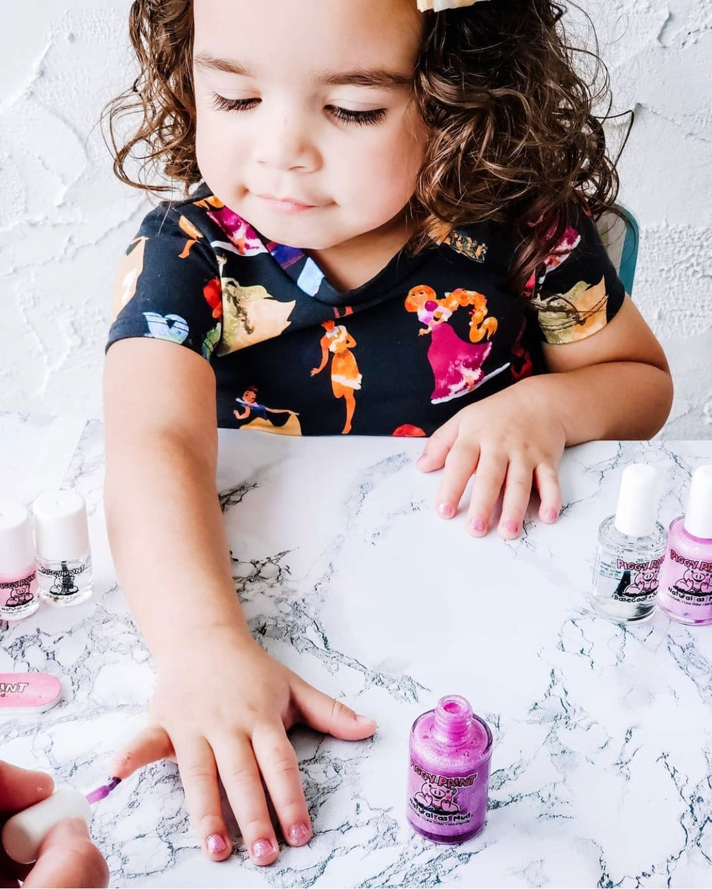 Child playing with nail polish on a marble surface