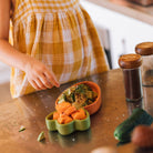 Child's hand reaching towards a bowl of food on a wooden table