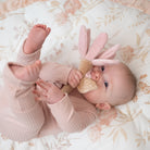 Baby lying on a floral blanket with a pink bunny toy