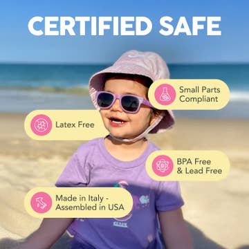 Child on a beach wearing sunglasses and a hat with safety certification badges.