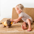 Child playing with a toy lion on a beige couch
