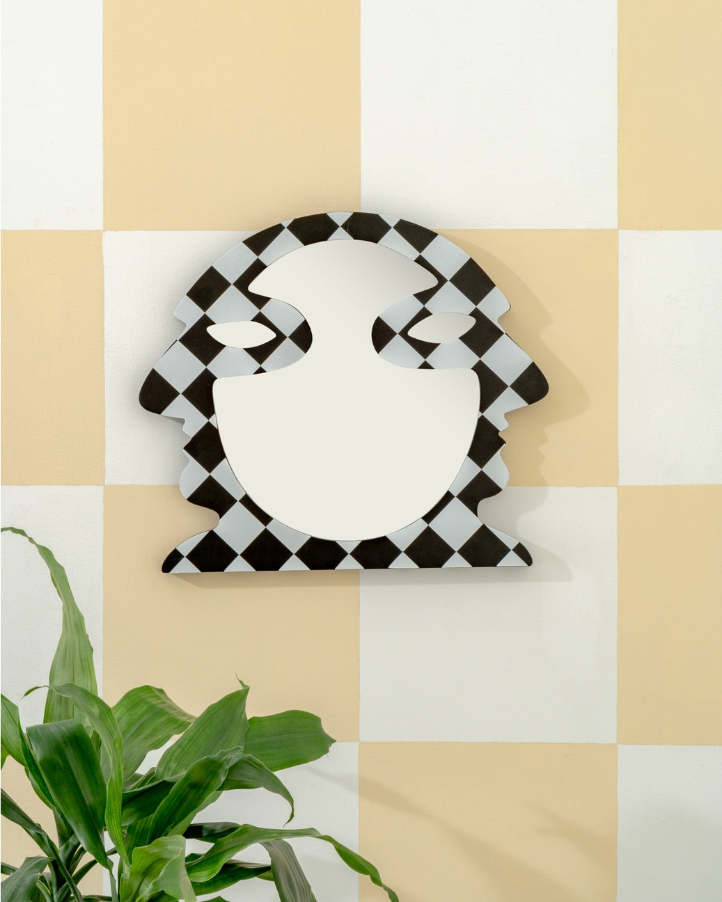 Decorative mirror shaped like a turkey on a checkered wall with a plant in the corner.