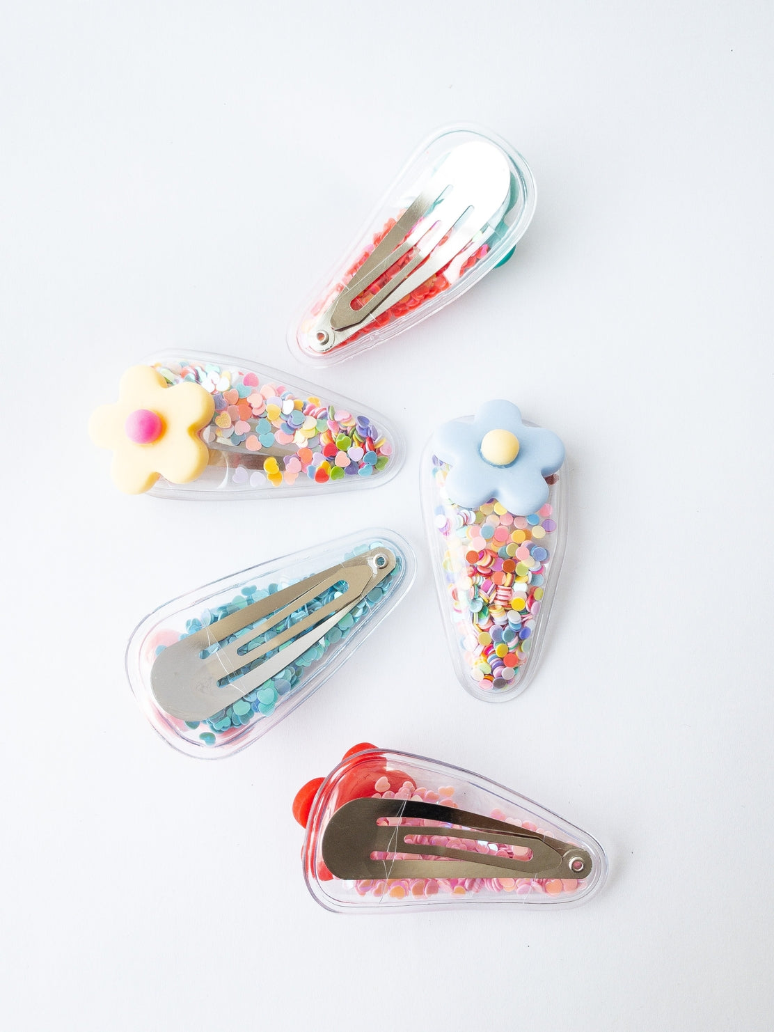 Set of colorful hair clips with decorative elements on a white background