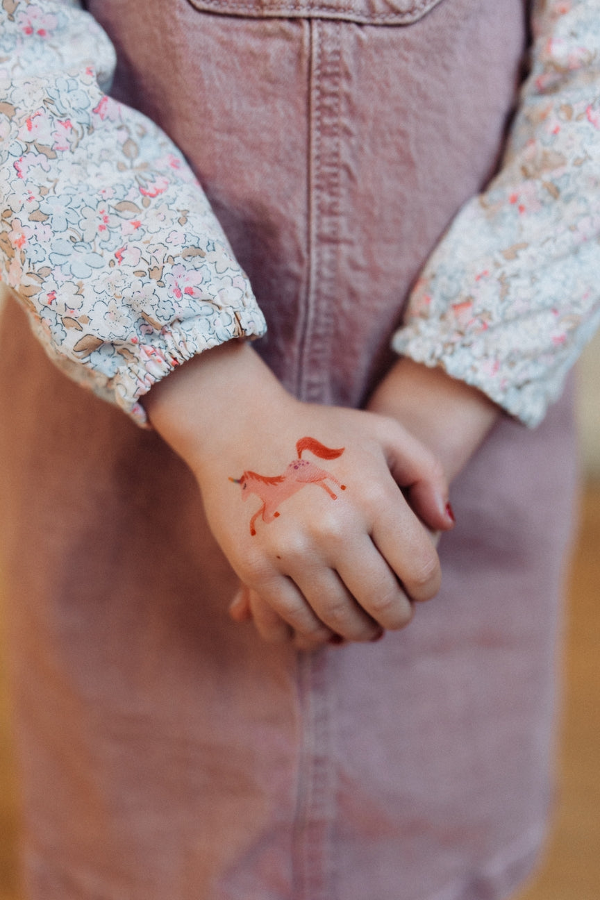 Person wearing a floral shirt with a small red tattoo on their wrist.