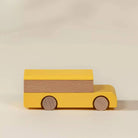 A minimalist wooden toy truck with a bright yellow body and a natural wood grain panel on top, set against a warm beige background.