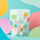 Packaging of 'Mini Drops' bath bombs with colorful design on a blue background