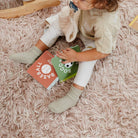 Child sitting on a pink carpet holding two books
