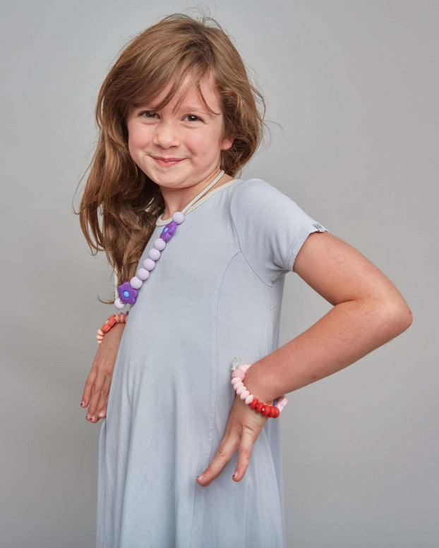 Young girl in a gray dress with jewelry on a gray background