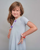 Young girl in a gray dress with jewelry on a gray background