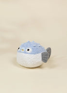 Stuffed toy resembling a bird with a blue head and gray wings on a beige background