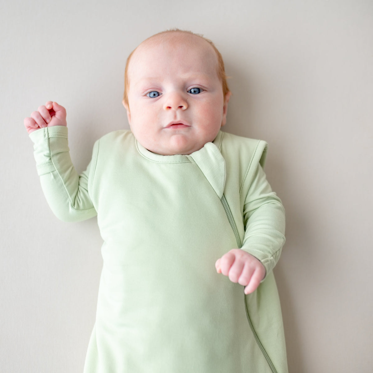 Baby wearing a light green onesie against a plain background