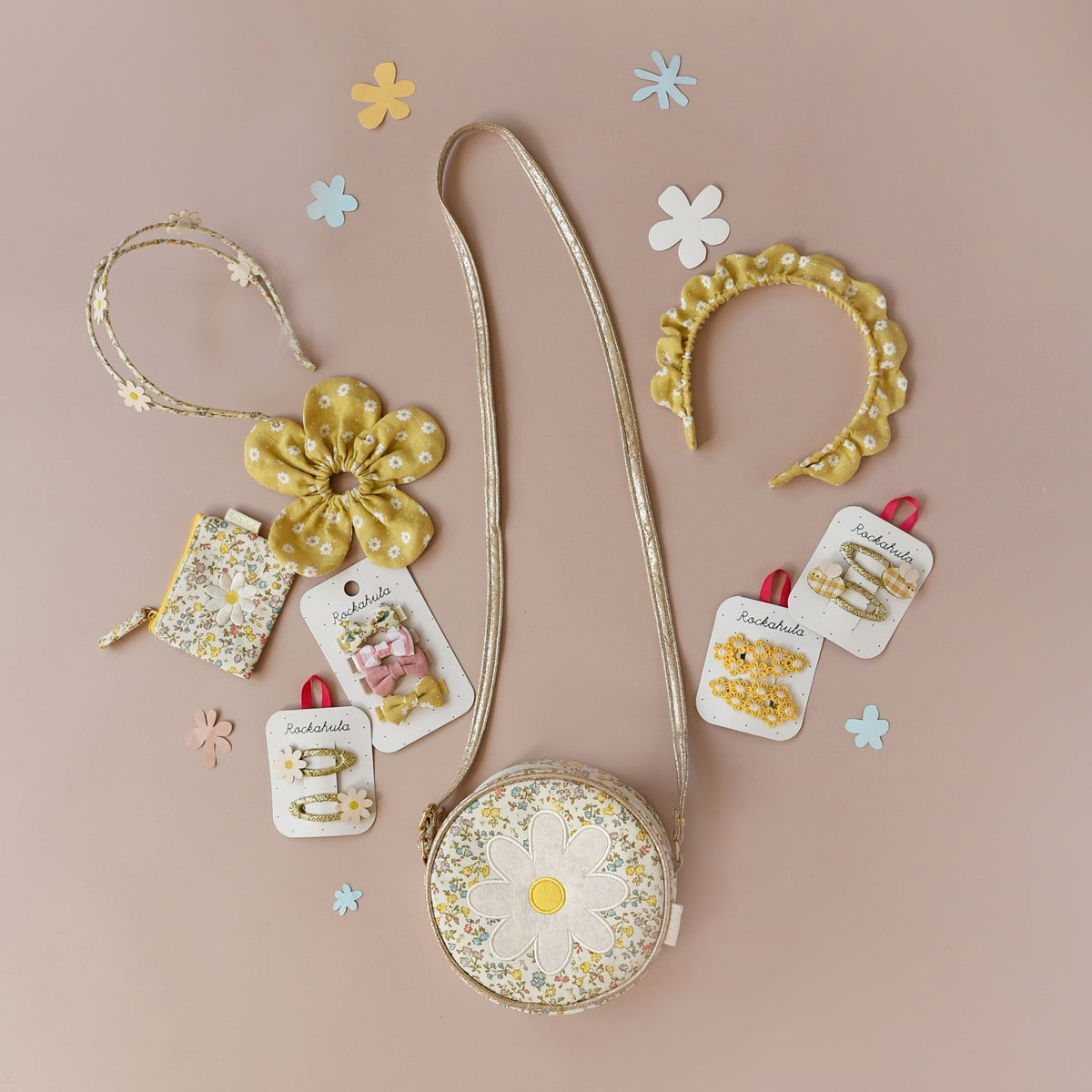 Small round bag with floral design, yellow flower accessory, and hair accessories on a beige background.