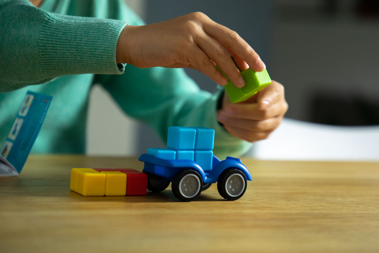Child playing with colorful building blocks on a wooden table